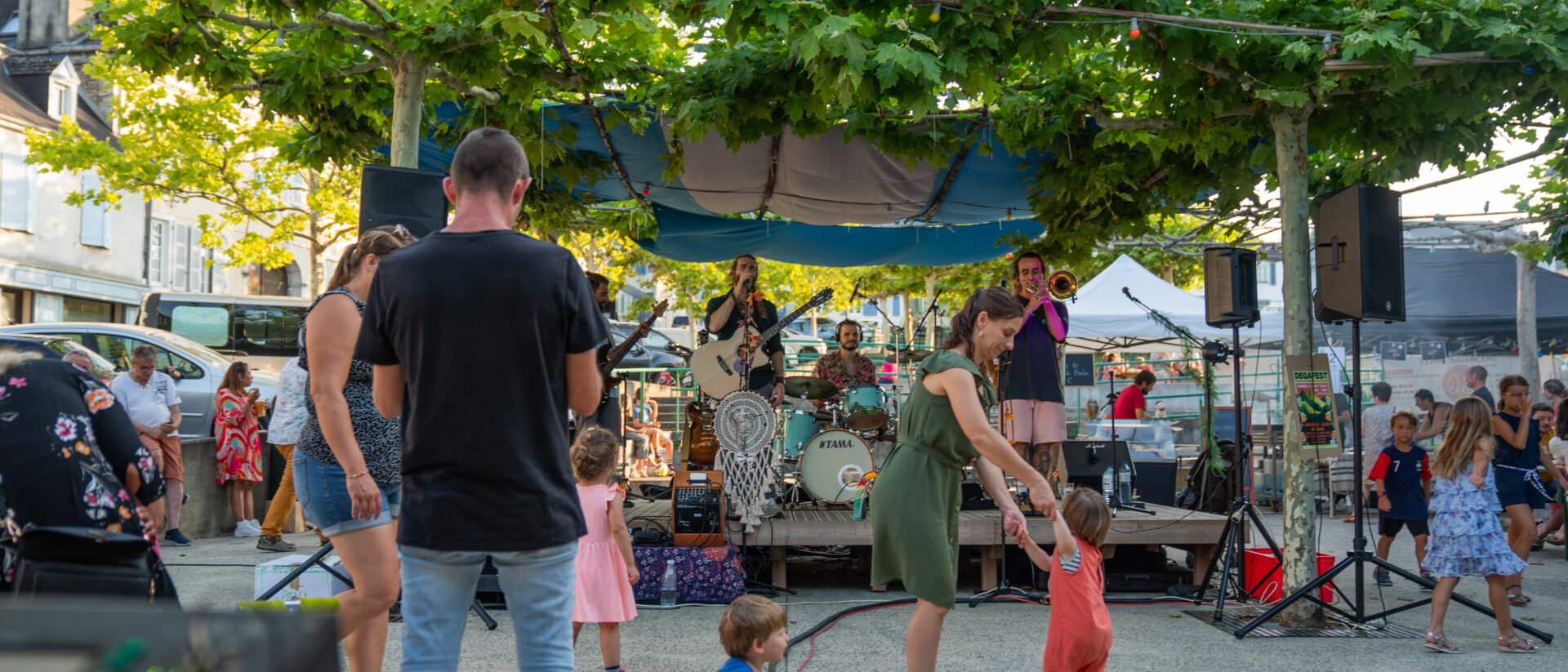 Une femme et sa petite fille dansant devant la scène d'un groupe de musique au marché des producteurs de pays de Monein. - Agrandir l'image, fenêtre modale