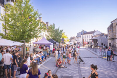 Foule au centre ville d'Orthez sur la place de l'église au milieu de chapiteau de commerçants installés pour l'occasion. - Agrandir l'image 1 sur 3, fenêtre modale