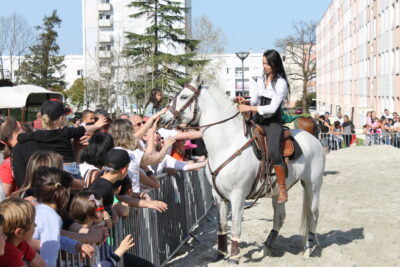 Jeune cavalière terminant son spectacle, va présenter son chevaux au public au bord des barrières de sécurité pour que tout le monde puisse le caresser. - Agrandir l'image 1 sur 3, fenêtre modale