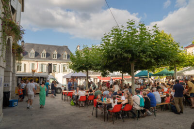 Plusieurs tables alignés avec des personnes en train de déguster de bons repas en échangeant tous ensemble. - Agrandir l'image 2 sur 3, fenêtre modale