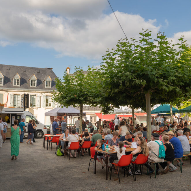 Plusieurs tables alignés avec des personnes en train de déguster de bons repas en échangeant tous ensemble.