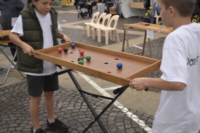 Deux jeunes enfants jouant à des jeux en bois où le concept est de lever une table en bois et de faire glisser des balles dessus en visant les trous pour les faire tomber. - Agrandir l'image 1 sur 3, fenêtre modale