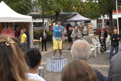 Intermittent du spectacle se tenant debout sur une caisse pour jouer une sorte de spectacle de magie à l'aide d'une canne, fasse à son public. - Agrandir l'image 2 sur 3, fenêtre modale