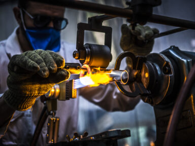Industriel équipé de protections pour travailler le verre directement sur des flammes à l'aide d'un chalumeau.