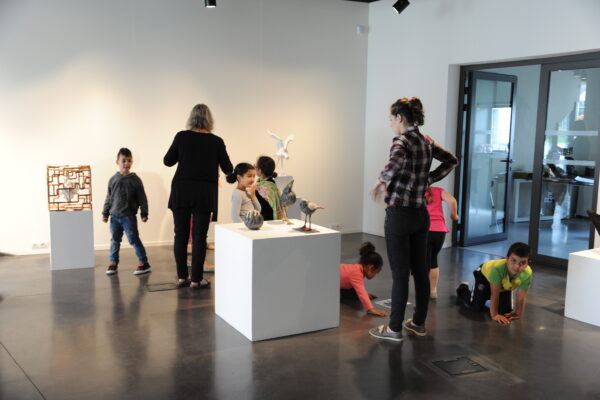 enfants visitant une exposition de sculptures d'oiseaux dans la galerie d'art