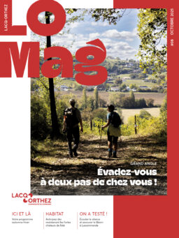 Page de garde du LO Mag avec écrit en haut à gauche LO MAG, une photo au centre à cheval sur un rectangle blanc à gauche et un rectangle rouge à droite, dans laquelle on distingue deux randonneurs de dos, dans un coin ombragé, avec en fond une commune rurale qui apparait. Le bas de la page de garde montre 3 sections "ici et là", "habitat" et "on a testé" pour teaser l'intérieur du magazine.