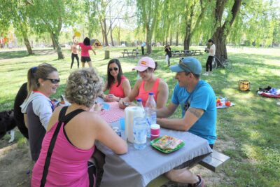 Groupe d'amis dégustant un pique-nique partagé sur l'une des tables ombragées de la Base de loisirs. - Agrandir l'image 2 sur 2, fenêtre modale