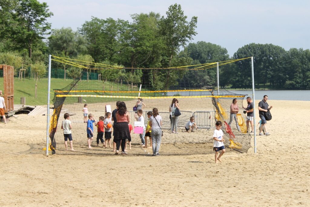 Groupe de jeunes enfants accompagnés d'adultes pour apprendre à jouer dans une structure peu commune appelée homeball. - Agrandir l'image, fenêtre modale