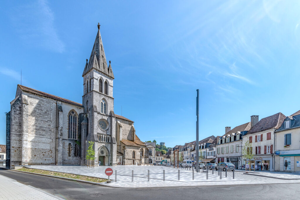 vue de la place saint-pierre devant l'église type gothique. A droite, de l'autre côté de la route, on aperçoit des commerces de restauration. La place est surélevée par rapport à la route à gauche de l'image et une petite marche est nécessaire pour la rejoindre - Agrandir l'image, fenêtre modale