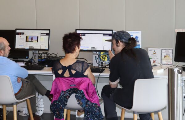 Un médiateurs des cyberbases est assis devant un ordinateur avec une dame demandant de l'aide pour se servir d'un ordinateur.