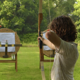 Jeune homme s'apprêtant à tirer une flèche dans la cible dans la zone de tir à l'arc.