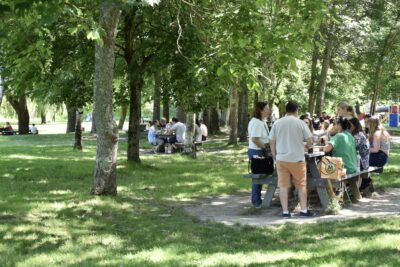 Vacanciers mangeant aux tables de pique-nique à l'entrée de la Base de loisirs. - Agrandir l'image 1 sur 2, fenêtre modale
