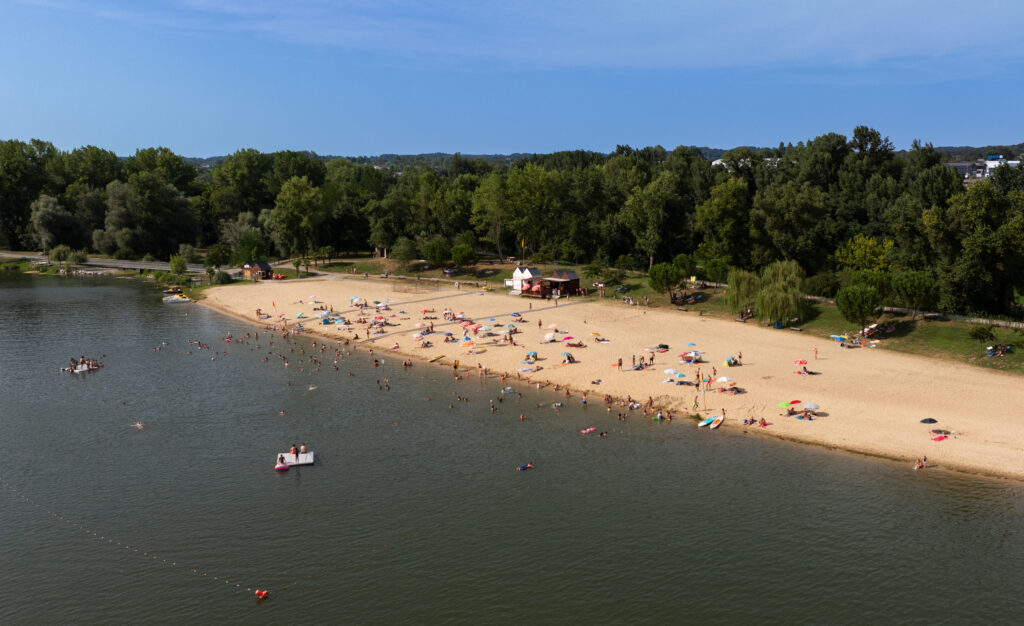 Vue du ciel de la plage de sable fin de la Base de loisirs et ses nombreux vacanciers, ainsi que du lac de Biron. - Agrandir l'image, fenêtre modale