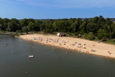 Vue du ciel de la plage de sable fin de la Base de loisirs et ses nombreux vacanciers, ainsi que du lac de Biron. - Agrandir l'image 4 sur 6, fenêtre modale