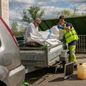 Deux agents de la déchetterie de Maslacq aidant un habitant à vider ses déchets depuis une remorque du véhicule.