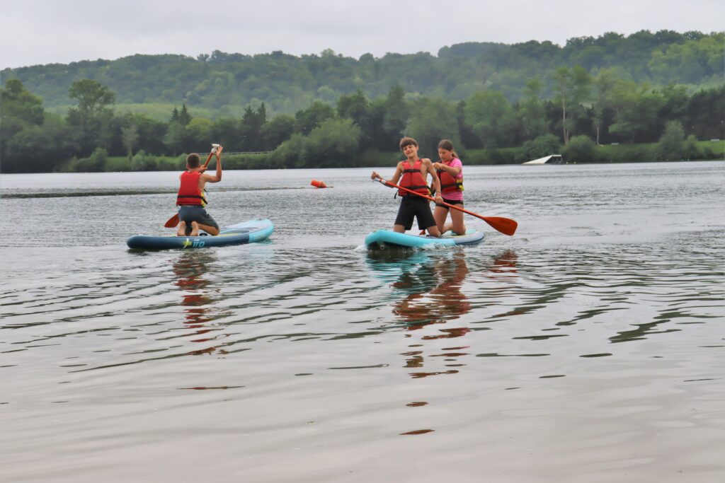 Deux vacanciers à genoux sur un paddle de location au milieu du lac de Biron. - Agrandir l'image, fenêtre modale