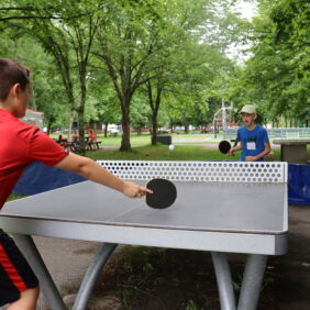 Deux jeunes garçons jouant une partie de ping-pong sur l'un des tables de la Base de loisirs.