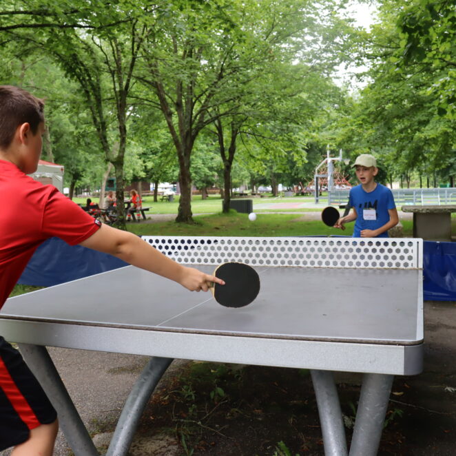 Deux jeunes garçons jouant une partie de ping-pong sur l'un des tables de la Base de loisirs.