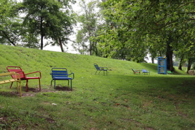 Des transats de toutes les couleurs disséminés à l'ombre des arbres et proche d'une boite à livres à la Base de loisirs. - Agrandir l'image 1 sur 2, fenêtre modale