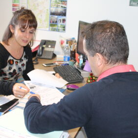 Deux personnes dont un habitant et une agente, dans un bureau, étant en train de remplir des documents officiels.