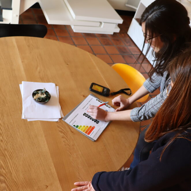 Deux jeunes femmes analysant les capacités d'isolation du logement dans lequel elles se trouvent avec un petit appareil.