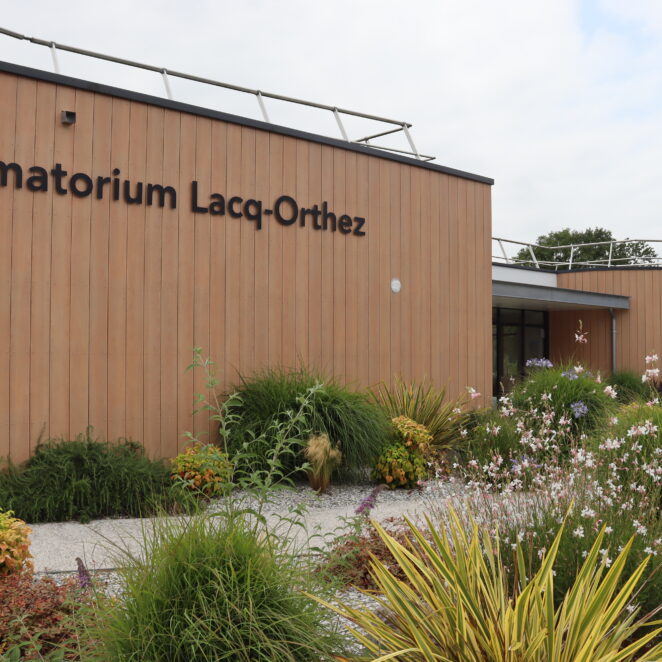 Façade du crématorium Lacq-Orthez avec un design sobre style bois et des plantations autour.