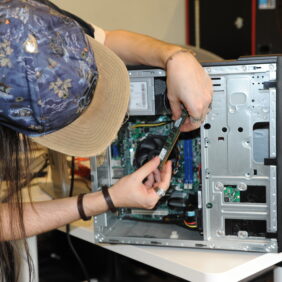 Personne proche d'une tour d'ordinateur fixe démonter en train d'analyser les pièces pour le réparer.