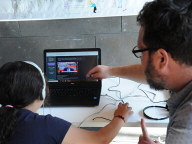 Un médiateur numérique guidant une jeune fille pour lui apprendre à se servir de son ordinateur et la sensibiliser aux usages.