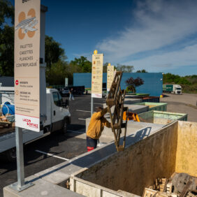 Habitant jetant dans la benne dédiée, des palettes en bois pour valoriser les matériaux.