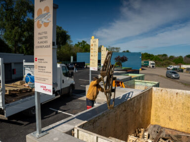 Habitant jetant dans la benne dédiée, des palettes en bois pour valoriser les matériaux.