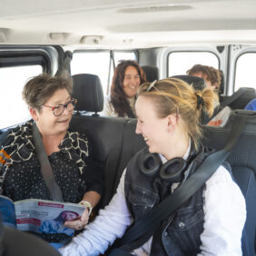 Cinq personnes de tout âges prennent le même minibus de transport à la demande pour se rendre à destination.