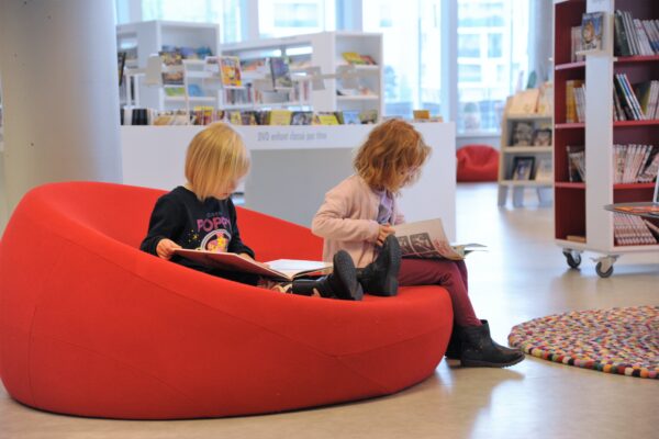 Deux enfants en bas âge lisant des BD sur des poufs à la médiathèque du MIX.