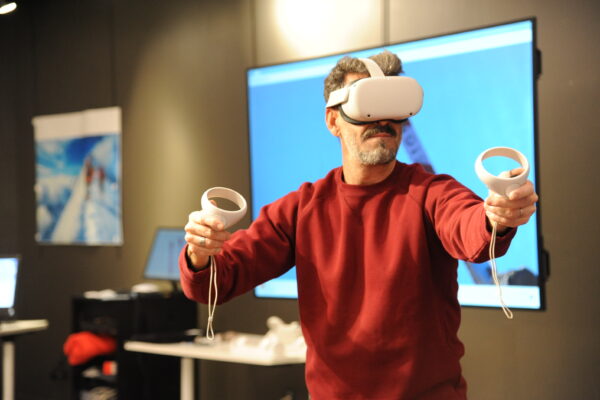 Homme jouant avec un casque et des manette adaptés aux jeux en réalité virtuelle.