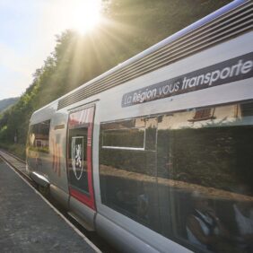 Un TER floqué avec l'identité de marque de la Région Nouvelle-Aquitaine, s'élançant à toute vitesse sur les rails