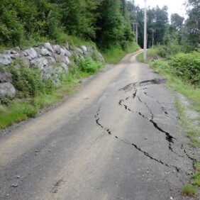 Grandes fissures dans le sol empiétant sur la chaussée sur une route de campagne