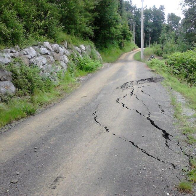 Grandes fissures dans le sol empiétant sur la chaussée sur une route de campagne