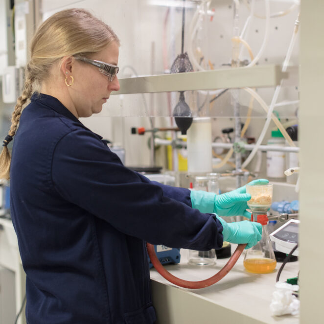 Jeune femme travaillant au sein d'une industrie et réalisant une expérience chimique.