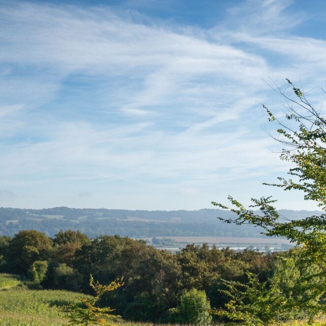 Grand ciel bleu avec quelques nuages blanc un jour d'été, avec une vue sur les campagnes du territoire.
