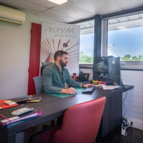 Jeune homme travaillant sur son ordinateur avec deux écrans dans un bureau.