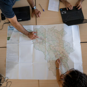Trois agents de la collectivité qui travaillent avec une cartographie du territoire sur un bureau.