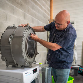 Professionnel réparant le tambour d'une machine à laver.
