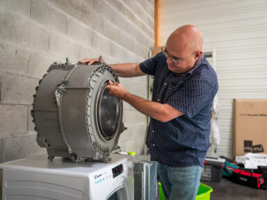 Professionnel réparant le tambour d'une machine à laver.