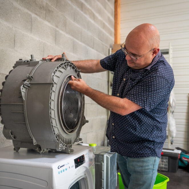 Professionnel réparant le tambour d'une machine à laver.