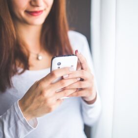 Jeune femme vue de face du nez à la taille en train de tapoter sur son téléphone mobile