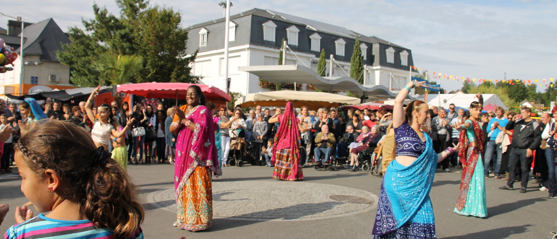 Femmes en habit traditionnel indien réalisant une danse dans un cercle formé par la foule.