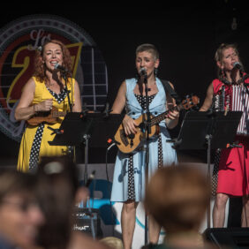 Groupe de trois chanteuses et musiciennes réalisant un concert sur scène au cœur d'Orthez.