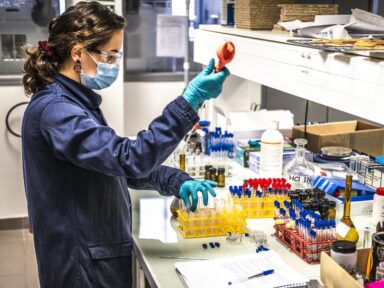 Jeune femme en tenue de sécurité pour réaliser des expériences chimiques sur son banc d'essai.