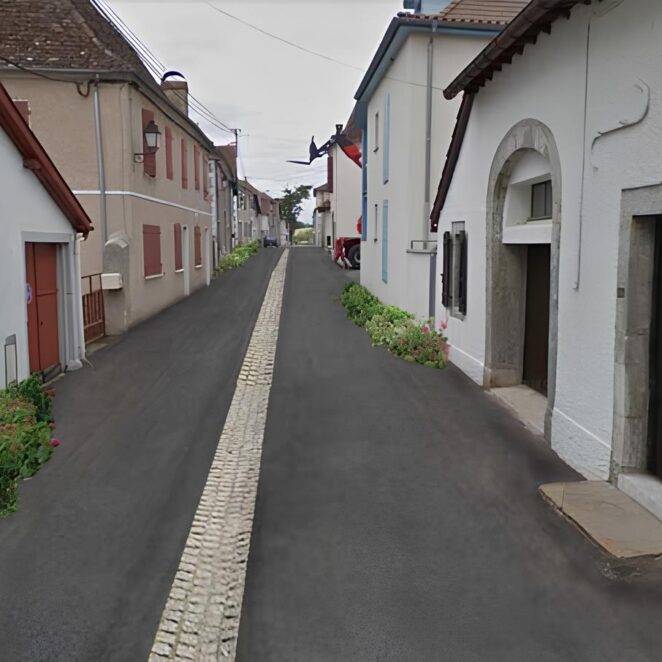 Vue après travaux montrant une route belle, avec une évacuation d'eau en son centre, et de belles plantations sur les bords des habitations.