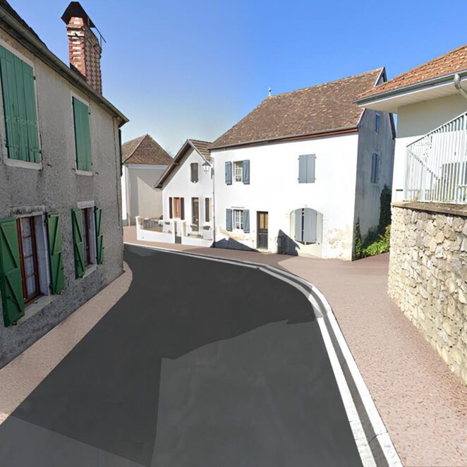 Vue après travaux montrant une route en vertical face à nous avec des maisons de part et d'autre, un revêtement neuf et des trottoirs aux couleurs clairs et assez larges pour les fauteuils roulant.