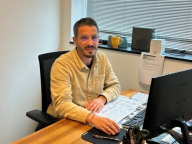 Mickael Galin pose devant son poste de travail équipé d'un ordinateur et de dossiers à la pépinière d'entreprises de Biron.